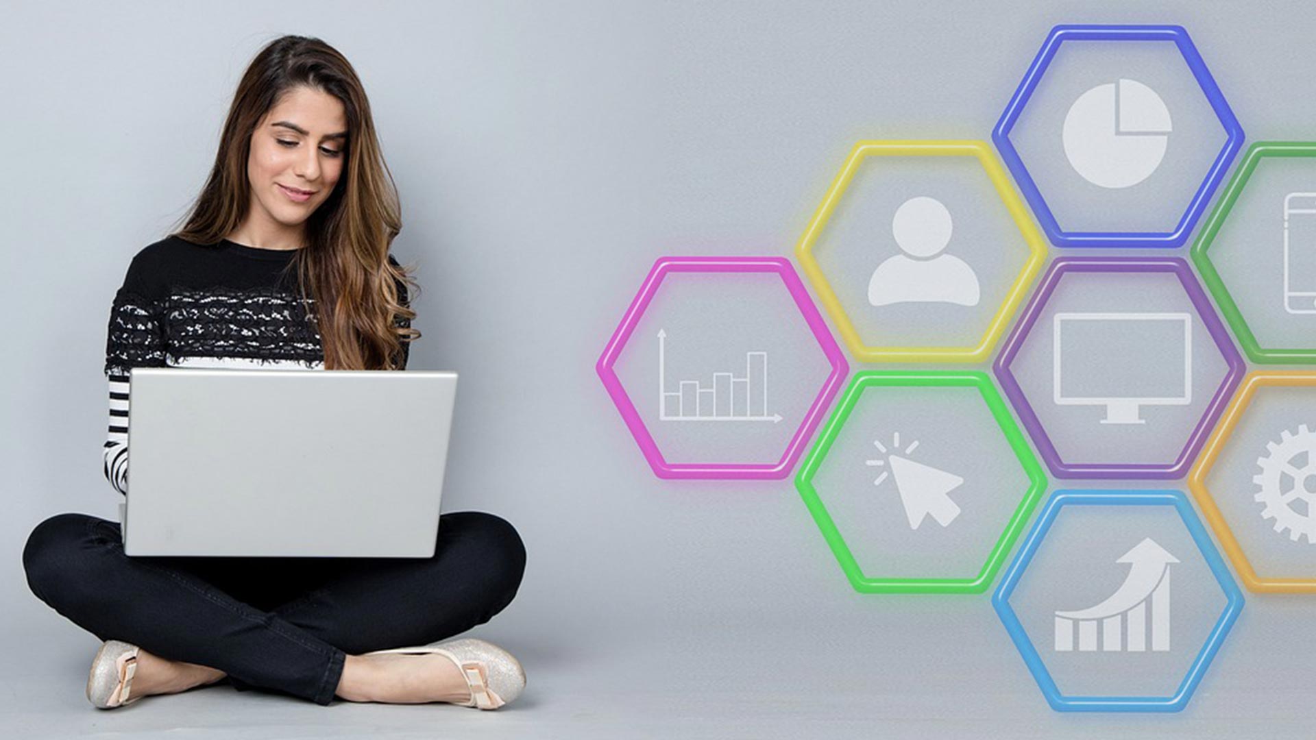 Eine Frau sitzt mit einem Laptop am Boden. Daneben befinden sich verschiedenfarbige Waben, die Marketing und Wachstum symbolisieren.